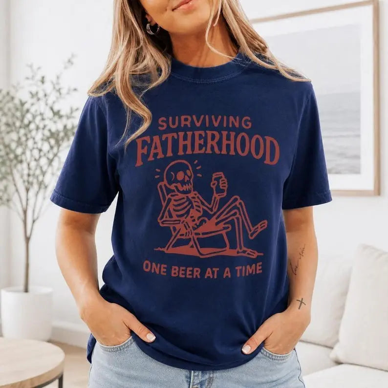 Surviving Fatherhood One Beer At A Time Skeleton Graphic T-Shirt | Navy Blue Funny Dad Humor Cotton Tee
